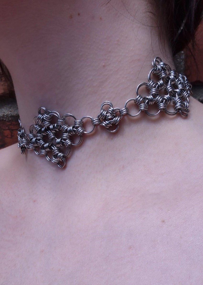 Zbliżenie na szyję osoby noszącej ręcznie robiony choker z kolczugi wykonany ze stali nierdzewnej, w stylu gotyckim, fantasy i średniowiecznym. Chainmaille biżuteria handmade.