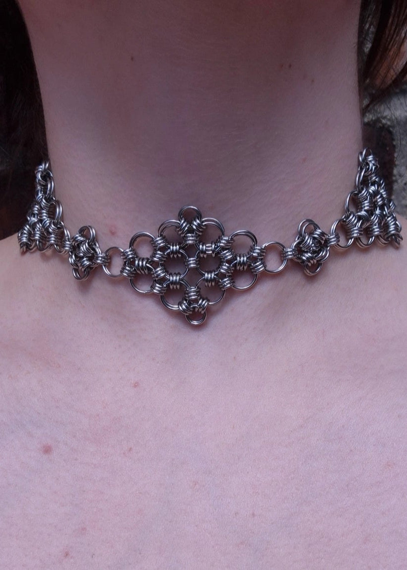 Zbliżenie na szyję osoby noszącej ręcznie robiony choker z kolczugi wykonany ze stali nierdzewnej, w stylu gotyckim, fantasy i średniowiecznym. Chainmaille biżuteria handmade.