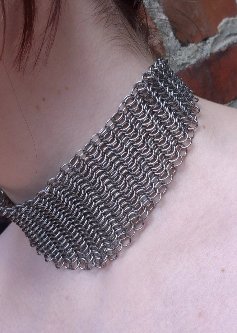 Zbliżenie na szyję z szerokim chokerem z kolczugi ze stali nierdzewnej, ręcznie robionym w stylu gotyckim, fantasy i średniowiecznym. Chainmaille biżuteria.
