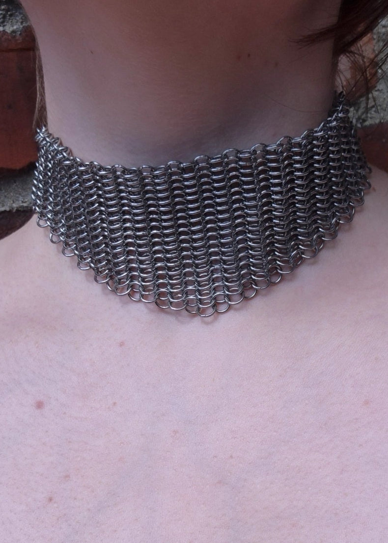 Zbliżenie na szyję z szerokim chokerem z kolczugi ze stali nierdzewnej, ręcznie robionym w stylu gotyckim, fantasy i średniowiecznym. Chainmaille biżuteria.