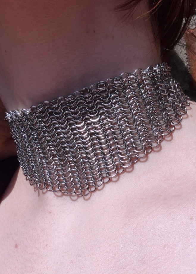 Zbliżenie na szyję z szerokim chokerem z kolczugi ze stali nierdzewnej, ręcznie robionym w stylu gotyckim, fantasy i średniowiecznym. Chainmaille biżuteria.