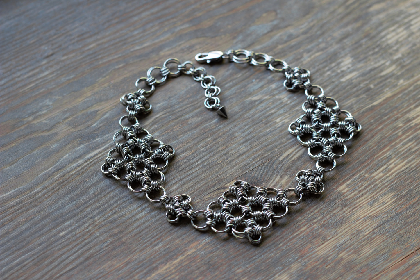 Choker z kolczugi w stylu fantasy położony na drewnianej powierzchni
