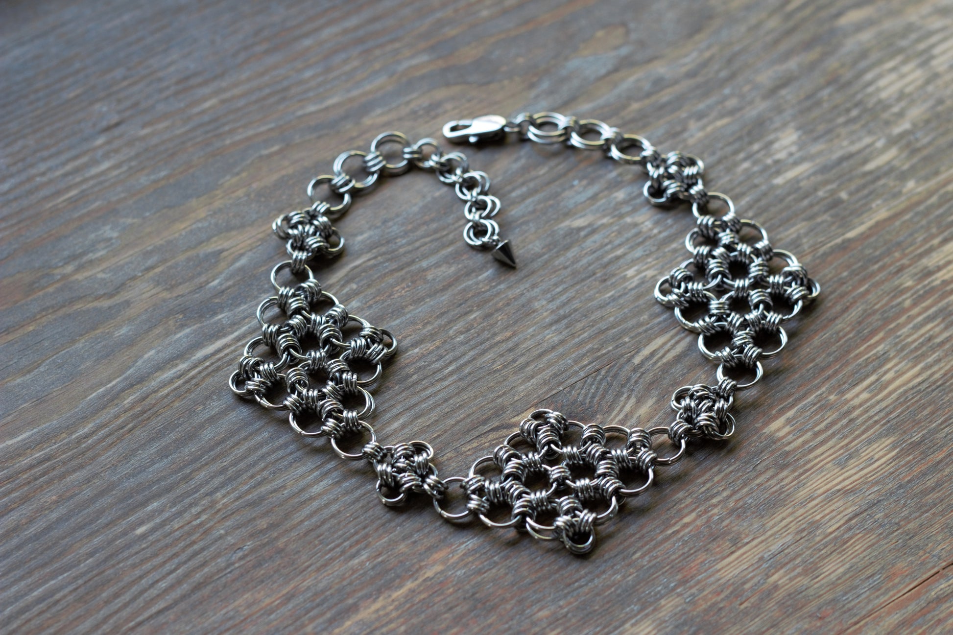 Choker z kolczugi w stylu fantasy położony na drewnianej powierzchni