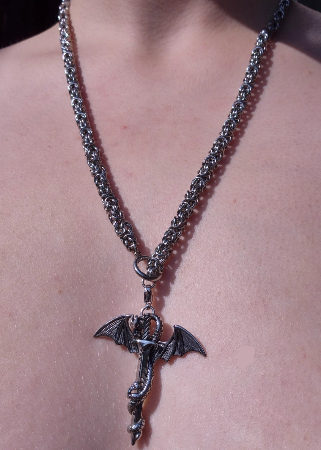 Gotycki naszyjnik z motywem smoka i miecza na masywnym łańcuszku chainmail, noszony jako klasyczny naszyjnik.